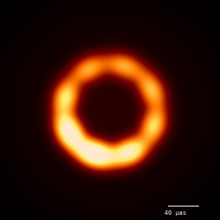 A simulated horizon-scale image: a glowing orange ring, brighter at the bottom, around a dark centre.